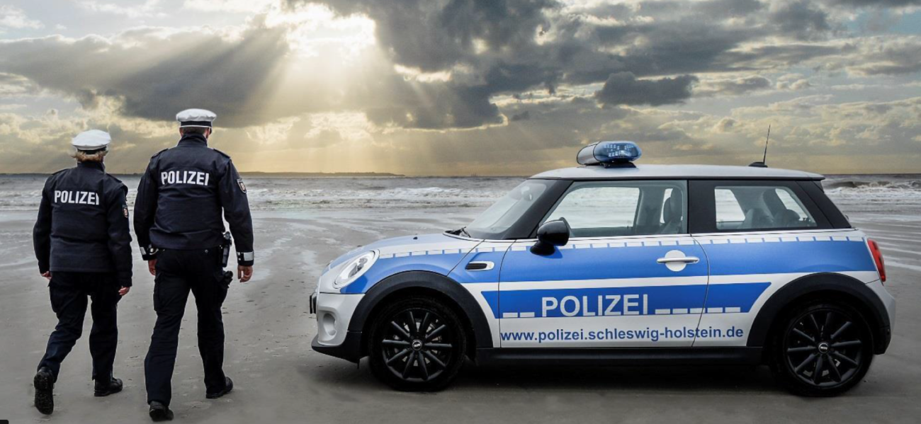 2 Polizisten mit einem Polizeifahrzeug